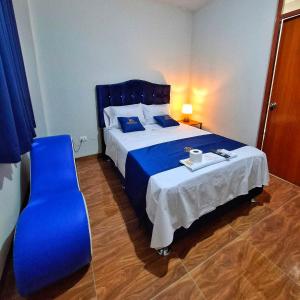 a bedroom with a blue bed and a blue chair at Delcor Suite in Piura