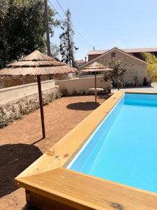 a swimming pool with an umbrella and a swimming pool at Encantos da Aldeia - Casa da Pedra in Oliveira de Azemeis