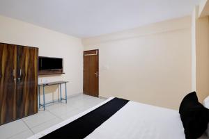 a bedroom with a bed and a desk and a tv at Hotel O M3M Paradise in Bhiwadi
