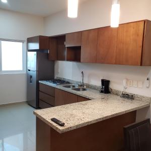 a kitchen with wooden cabinets and a granite counter top at Torre Monaco en Sabalo Country in Mazatlán +12 photos