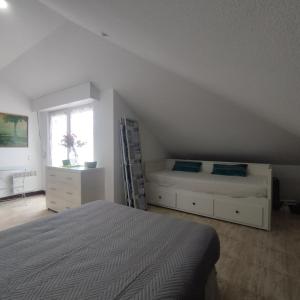a white bedroom with two beds and a window at Atico en Ajo Cantabria in Ajo