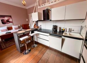 a kitchen with white cabinets and a bed in a room at Royal Rose Suite in zentraler Lage in Bremen