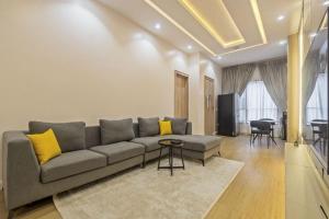 a living room with a gray couch and yellow pillows at Zuma Tan in Lagos +1 photo