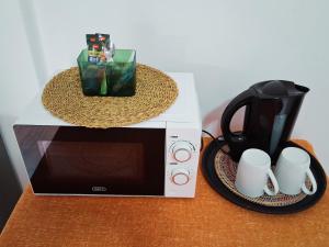 a counter with a microwave and a coffee pot and mugs at 30 on Latham Guesthouse in Klerksdorp