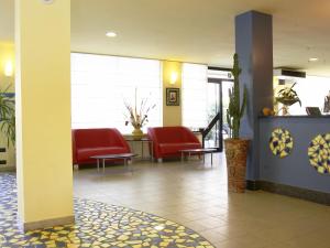 une salle d'attente avec des chaises rouges dans un hôpital dans l'établissement Hotel Reno, à Lido di Savio