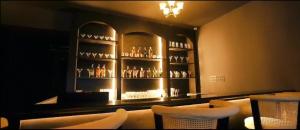 a bar with white chairs and glasses on shelves at Hotel Delw in Bacha