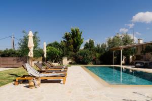 a swimming pool with lounge chairs and an umbrella at Jacomo Private Villa in Alykes