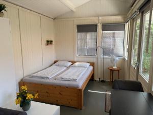 a bedroom with a bed in a room with windows at Tiny House Madame Jeanette nabij centrum en zee in Zandvoort