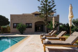 a villa with a swimming pool and lounge chairs at Jacomo Private Villa in Alykes