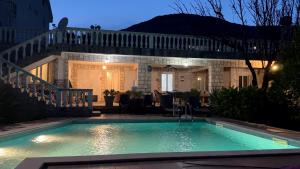 a swimming pool in front of a house at night at Andolly Apartments in Bar
