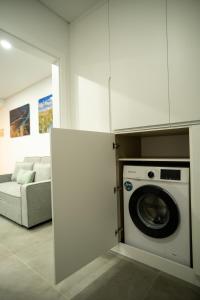 a kitchen with a washing machine and a couch at Côa River Apartment in Vila Nova de Foz Coa