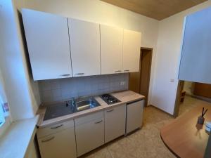a kitchen with white cabinets and a sink and a table at Il tempio del Gusto in Oelsnitz