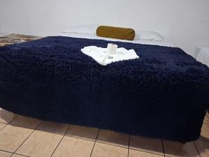 a bed with a blue blanket with a robe on it at hotel kasa kamelot parque in Quetzaltenango