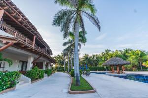a resort with a palm tree next to a swimming pool at Escondite condominios in Zihuatanejo