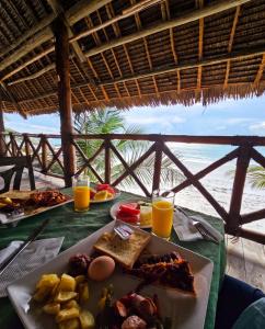 a table with a plate of food and orange juice at Isla Bonita Zanzibar Beach Resort in Matemwe