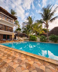 a swimming pool in front of a hotel with palm trees at Isla Bonita Zanzibar Beach Resort in Matemwe