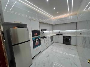 a white kitchen with a refrigerator and a dishwasher at Oran Choupot boulevard principale in Oran