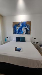 a bedroom with a large white bed with a painting on the wall at Suite Marina Gallega in Oya