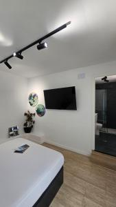 a white room with a bed and a flat screen tv at Suite Marina Gallega in Oya