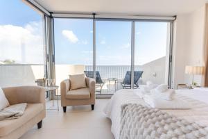 a white bedroom with a large bed and a chair at Casa Rosa Panoramic Seaview in Lagoa