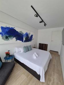 a bedroom with a large white bed and a blue painting at Suite atlántica in Oya +19 photos