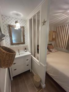 a bedroom with a bed and a sink and a mirror at Le Nid de Lou in Aire