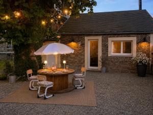 a patio with a table and chairs and an umbrella at Le Nid de Lou in Aire