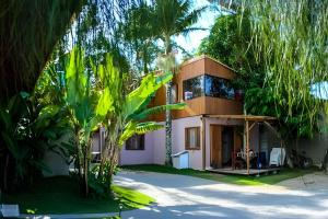 a house with palm trees in front of it at Chalés da Guarda do Embaú in Guarda do Embaú