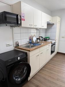 a kitchen with a washing machine and a sink at GARLAND Rooms in Bremen
