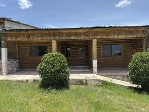 a wooden house with a sign on the front of it at Hotel Nuevo Barrancas del Cobre in Creel +1 photo