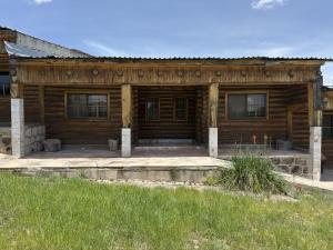 a wooden house with a porch and a lawn at Hotel Nuevo Barrancas del Cobre in Creel