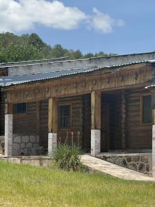 an old log cabin with a porch and grass at Hotel Nuevo Barrancas del Cobre in Creel