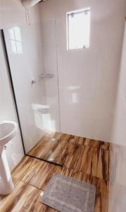 a bathroom with a shower and a wooden floor at Chalé do Campo in Palmeira