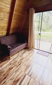 a room with a couch on a wooden floor with a window at Chalé do Campo in Palmeira +2 photos