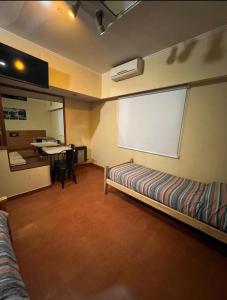 a room with a bed and a table with a window at Hotel Lido in General Rodríguez