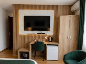 a bedroom with a desk with a television on a wall at Pensiunea Nobila Băile Figa in Beclean