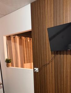 a television hanging on a wooden wall with books at Terrazas Guest House-Hostal in Suchitoto