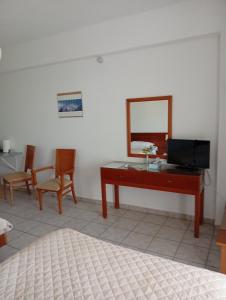 a bedroom with a desk and a mirror and chairs at Gikas Apartments Triple Studio Garden View A2 in Marmari