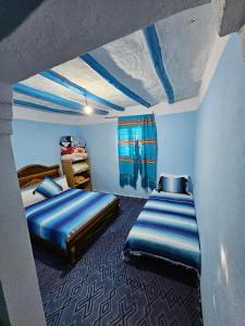 two beds in a room with blue walls at Gîte El houmar in Tanakoub