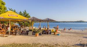 a group of people sitting on a beach with umbrellas at Apartment Sea in Galižana