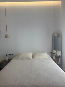 a white bedroom with a bed with two pendant lights at 2-bedroom villa Odysseus in Antiparos