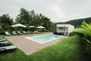 a swimming pool in a yard with chairs and umbrellas at Casas Peralta - Outeiro in Arouca