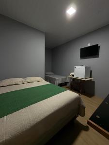 a bedroom with a bed and a flat screen tv at Chalé por do Sol in Aracaju