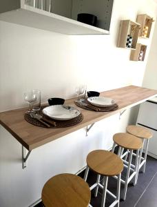 a wooden table with chairs and plates and wine glasses at Rose CosyHome Paris Champs in Champs-sur-Marne