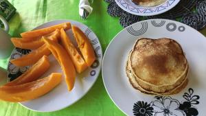 two plates of food with pancakes andangerries on a table at Navi Homestay in Naisisili +3 photos