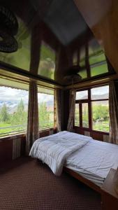 a bed in a room with two windows at Bagh Rustum Guest House in Holshāl +8 photos