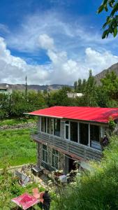 a house with a red roof in a field at Bagh Rustum Guest House in Holshāl