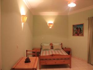 a bedroom with a bed and a table and lights at K.méléon-Hôtel in Ivato