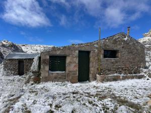 a stone building with a green door in the snow at Rinconcito Serrano in Mina Clavero