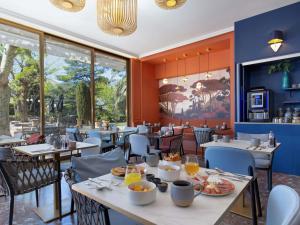 a restaurant with tables and chairs with food on them at Mercure Marseille Centre Bompard La Corniche in Marseille